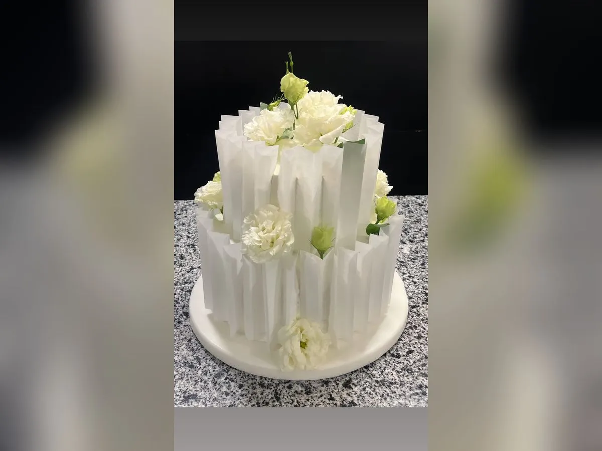Beyaz pileli kaplaması ve canlı çiçekleriyle iki katlı özel tasarım pasta