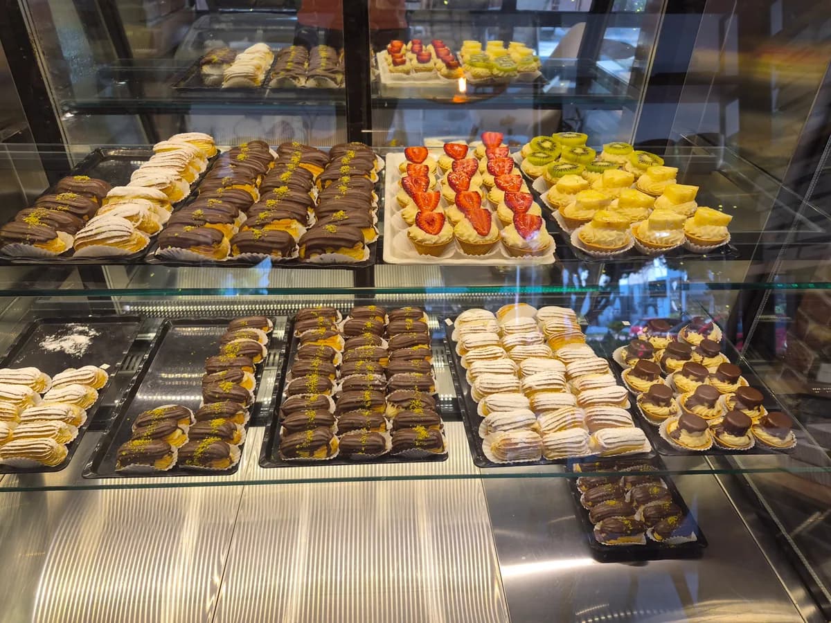 Vitrinde sıralanmış ekler, profiterol ve meyveli tartoletler